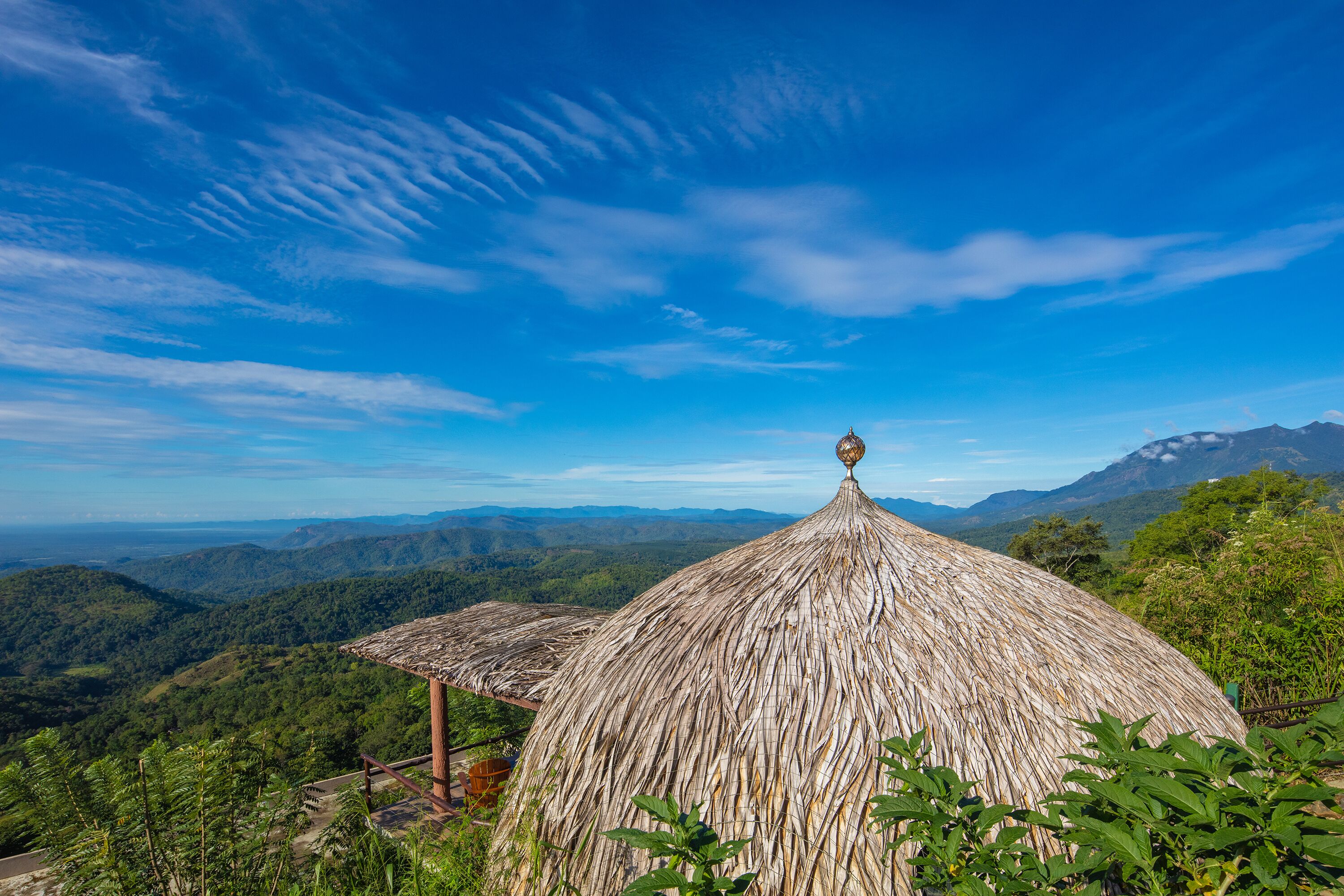 A thatched-roof hut with a view of a mountainous landscape.