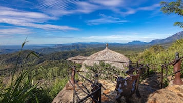 Una escalera de piedra conduce a una construcción con techo de paja, con vistas panorámicas a las montañas.