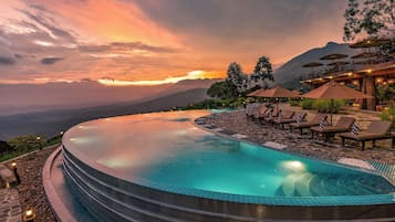 Una piscina al aire libre, sombrillas, sillones reclinables de piscina