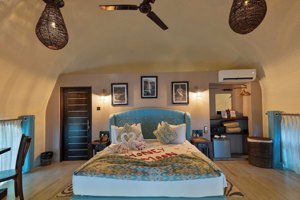 Ein Schlafzimmer mit einem Bett, einem Deckenventilator, einer Wand-Klimaanlage und gerahmten Bildern an der Wand.