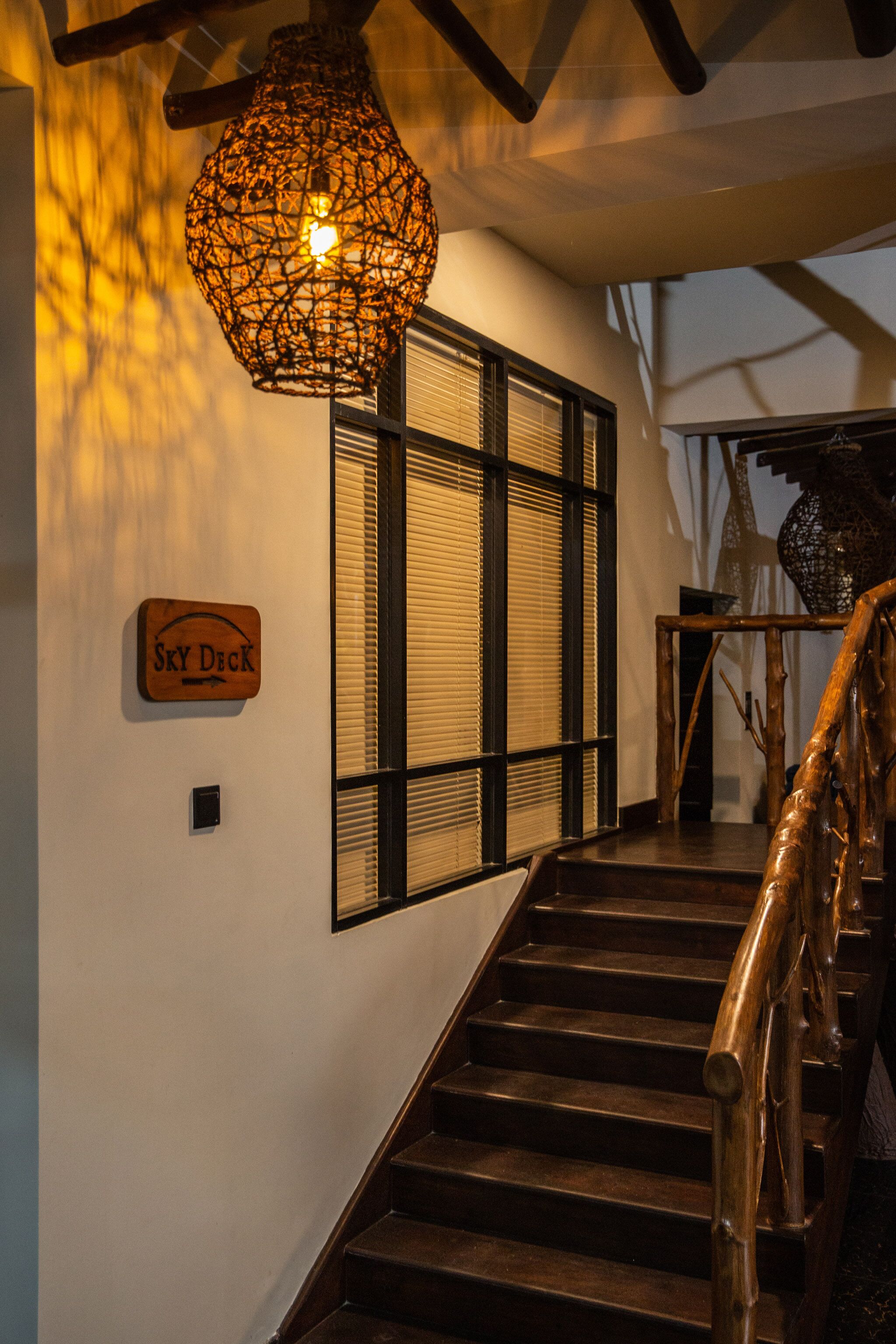 Una escalera de madera con peldaños y barandilla, que lleva a un espacio con un letrero que dice "Sky Deck".