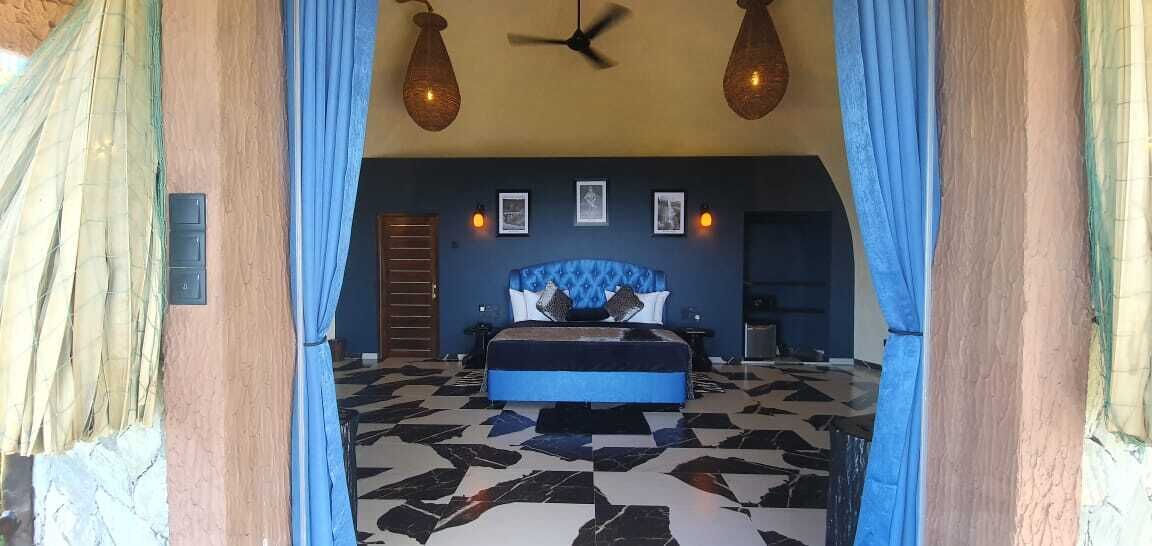 A bedroom with a bed, a ceiling fan, and a patterned floor.