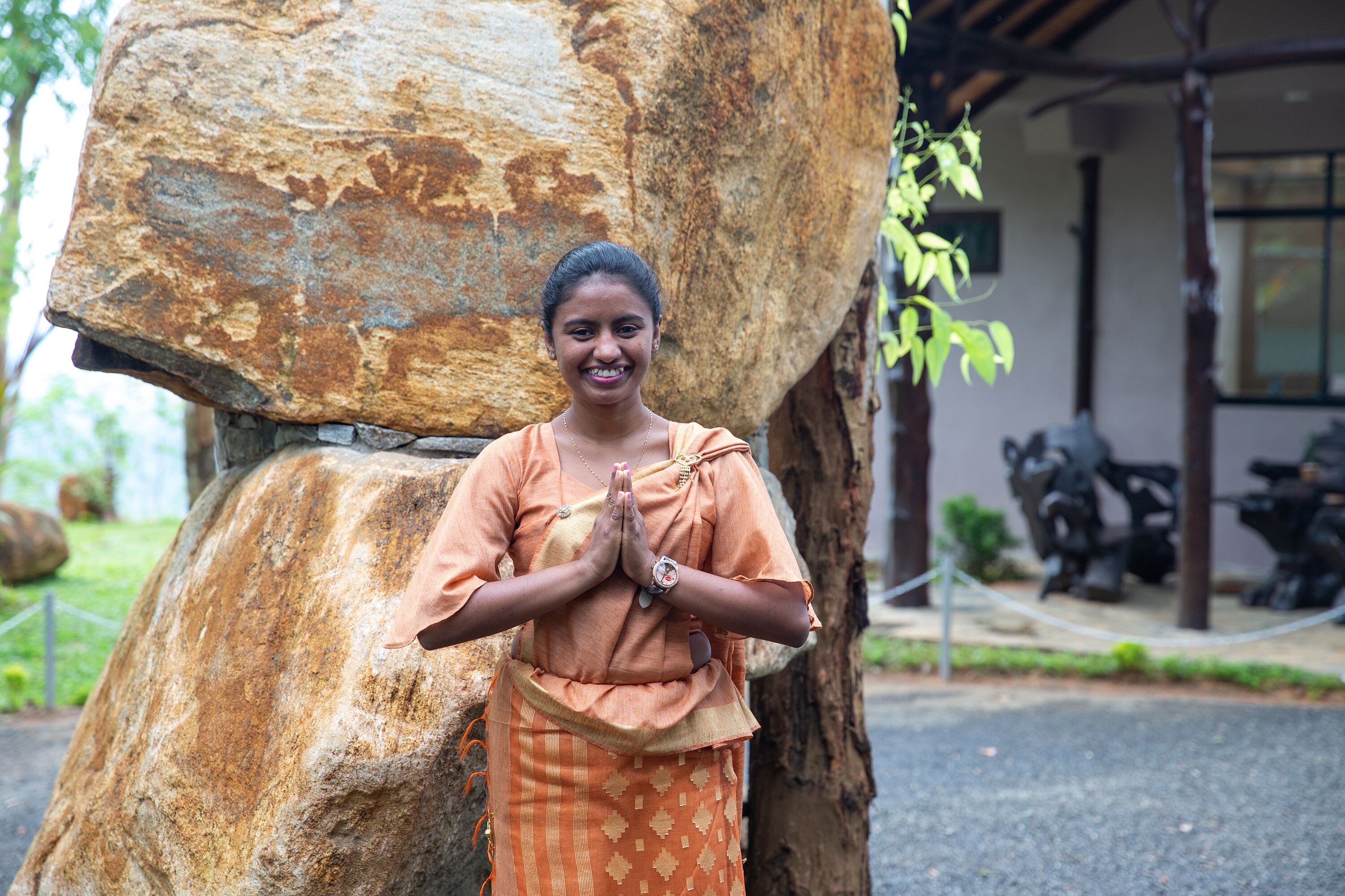 A person standing in front of a large rock formation, wearing traditional attire.