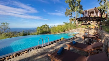 Una piscina al aire libre, sombrillas, sillones reclinables de piscina