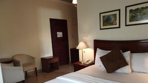 A hotel room with a large bed, a chair, a desk, a lamp, and two framed pictures on the wall. - Casa Estrella Hotel (Abuja)