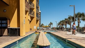 A swimming pool with a clear blue water feature, a sun lounger, and a palm tree-lined deck. - Direct oceanfront pools hot tubs downtown Myrtle Beach (Myrtle Beach)