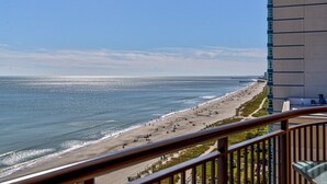 A beach view from a balcony with a railing, a pier in the distance, and a tall building to the right. - Direct oceanfront pools hot tubs downtown Myrtle Beach (Myrtle Beach)