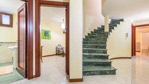 A spacious interior with a marble staircase, a wooden door, and a wall-mounted telephone.