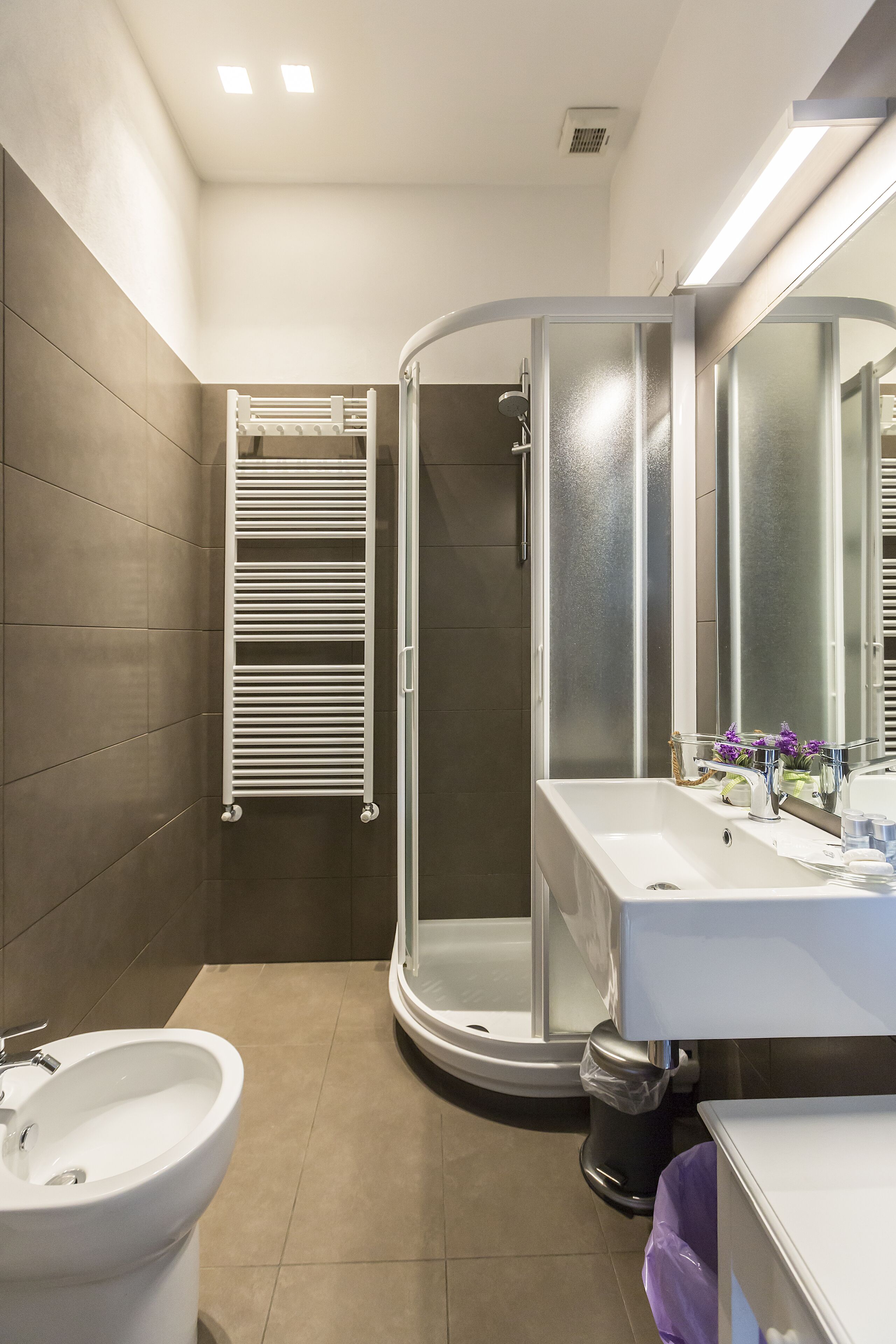 A modern bathroom with a shower, toilet, sink, and towel rack.