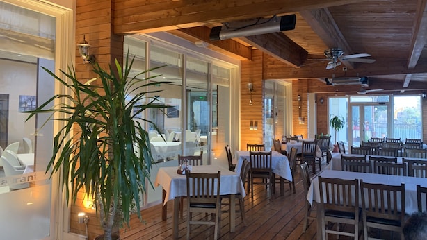A restaurant with wooden interiors, tables set with white tablecloths, and potted plants. - City Hotel Plovdiv (Plovdiv)