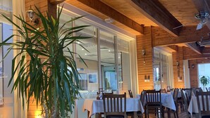 A wooden interior with tables and chairs, a potted plant, and a ceiling fan. - City Hotel Plovdiv (Plovdiv)