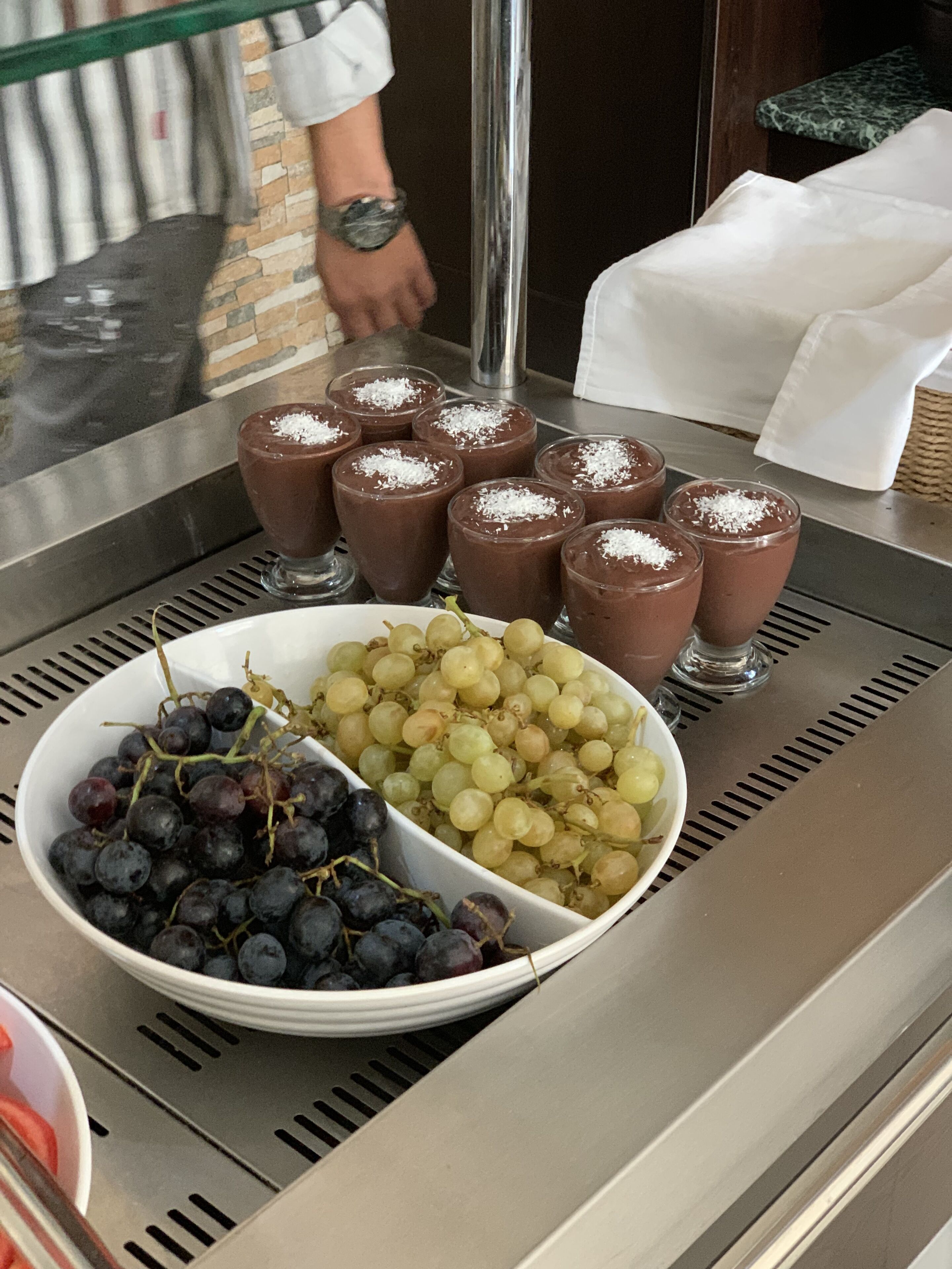 A buffet with chocolate desserts and a bowl of mixed grapes.