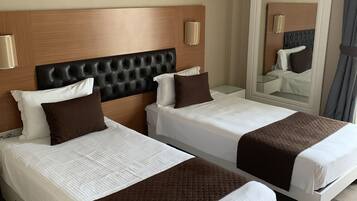 A hotel room with two beds, a wooden headboard, a large painting of a pier, and a mirror on the wall.