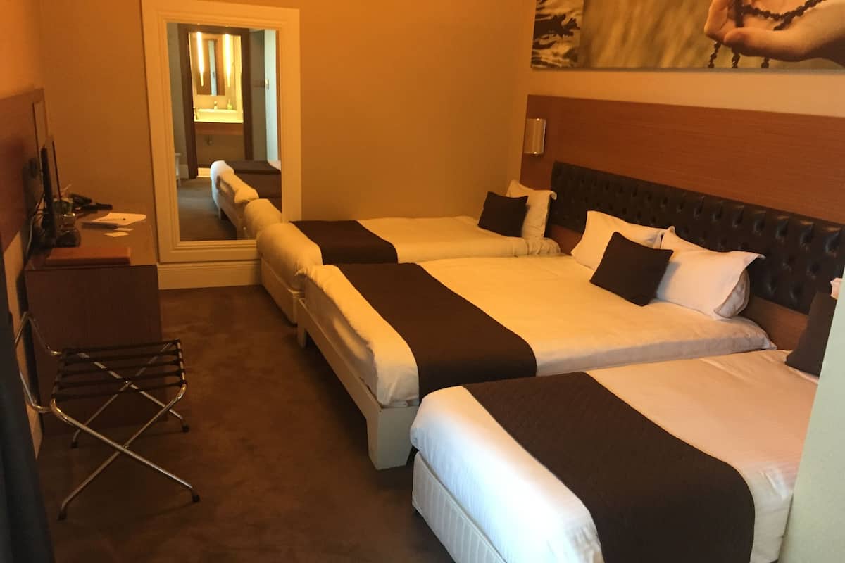 A hotel room with two beds, a desk, and a chair.