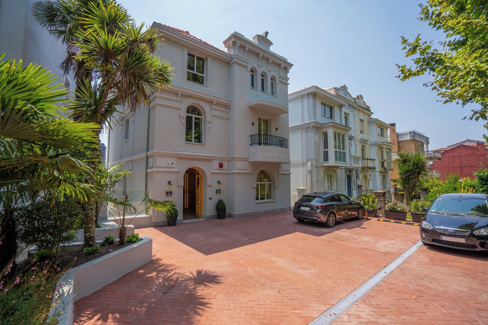 A multi-story building with a central entrance, a driveway, and a car parked in front.