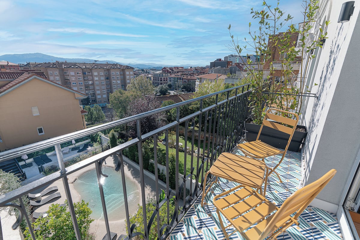 Ein Balkon mit Blick auf einen Swimmingpool, einen Garten und umliegende Gebäude.