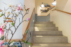 A staircase with a patterned railing, a wall-mounted light fixture, and a decorative plant. - Sercotel El Balcón de la Bahía (Santander)