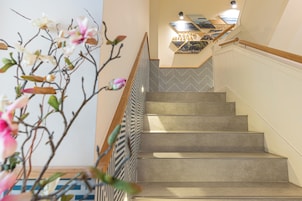 A staircase with a patterned railing, a wall-mounted light fixture, and a decorative plant.