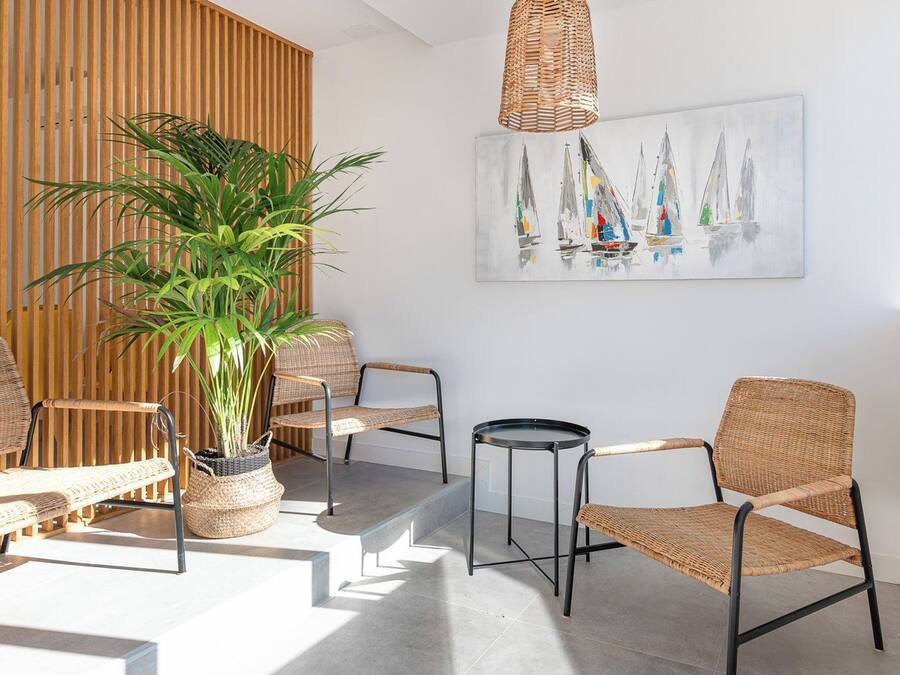 A modern interior with wicker furniture, a potted plant, and a sailboat painting.