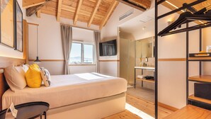Un dormitorio con cama, televisión, ventana y techo de madera.