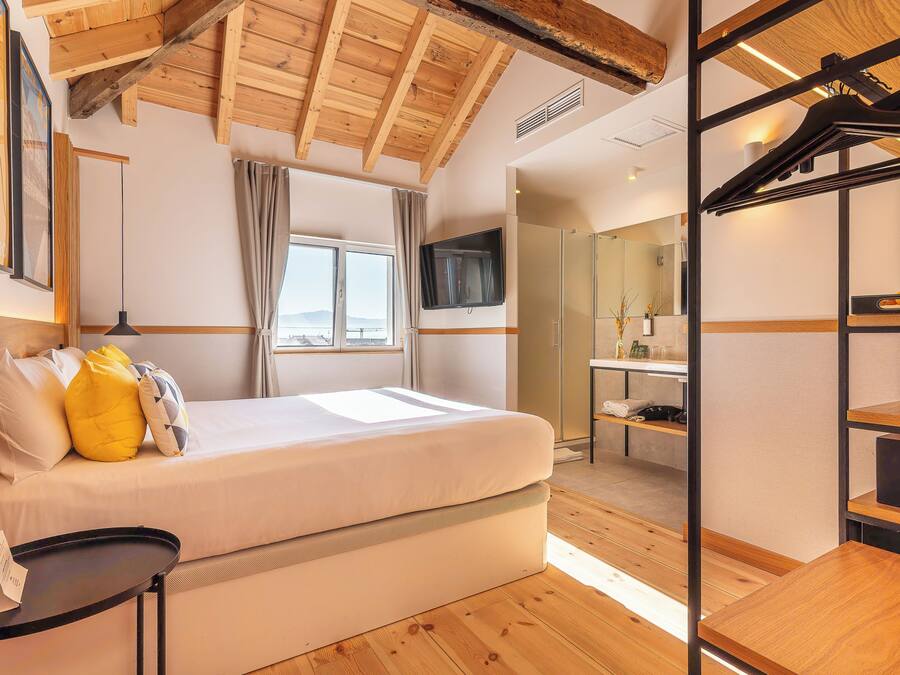 Une chambre à coucher avec un lit, une télévision, une fenêtre et un plafond en bois.