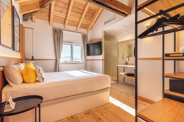 Un dormitorio con cama, televisión, ventana y techo de madera.