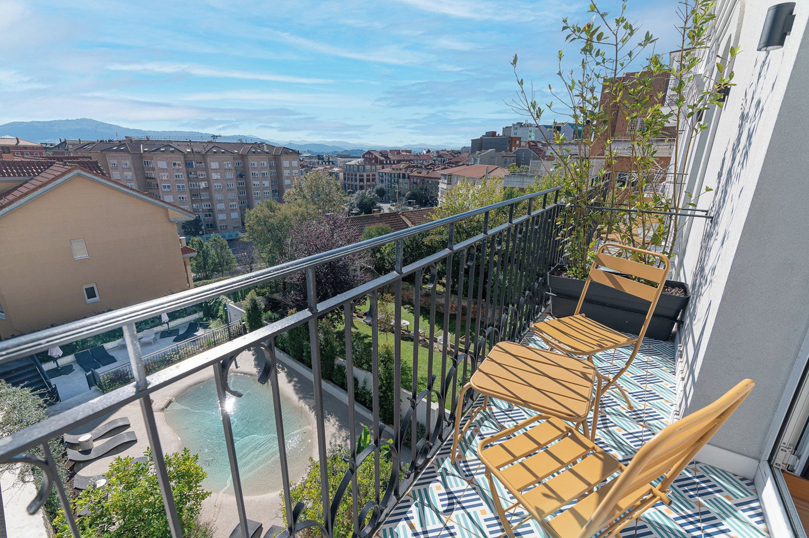 Un balcón con vistas a una piscina y edificios circundantes.