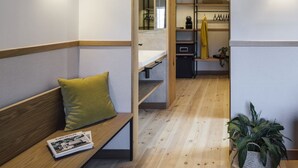 Un interior moderno con un banco de madera, una planta en maceta y vistas a una zona de cocina.