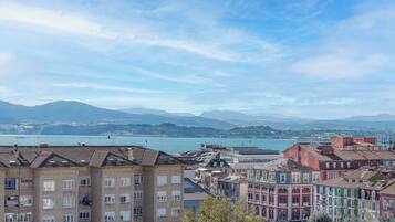 A coastal cityscape with colorful buildings, a bridge, and a body of water.