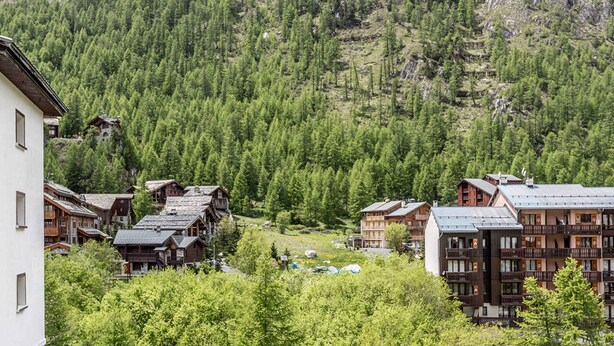A mountain village with traditional wooden buildings, a ski slope, and a view of the surrounding mountains. - Central apartment, near slopes, 10 pers, WiFi (Val-d'Isère)
