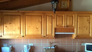 Une cuisine avec des meubles de rangement en bois, un lave-linge, un four et un four à micro-ondes.