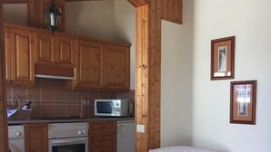 Un salon chaleureux avec un fauteuil en cuir et un coin repas doté de meubles en bois et d’un four à micro-ondes.