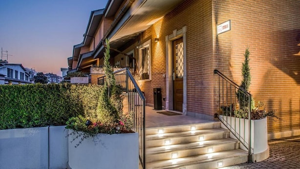 Un bâtiment moderne avec une façade en briques, un escalier illuminé menant à l’entrée et une enseigne au-dessus de la porte.