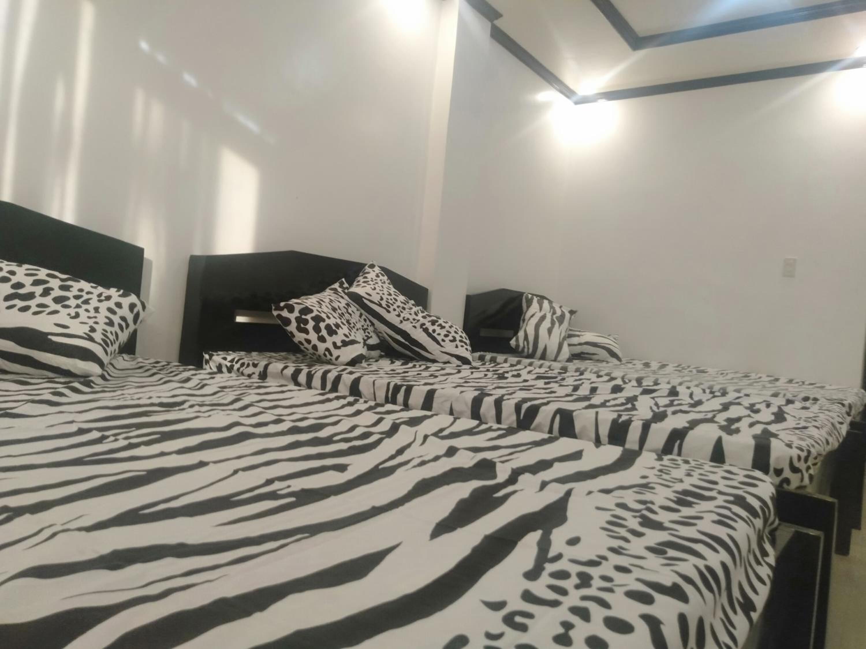 A hotel room with a zebra-patterned bedspread, a dark headboard, and a simple, clean design.