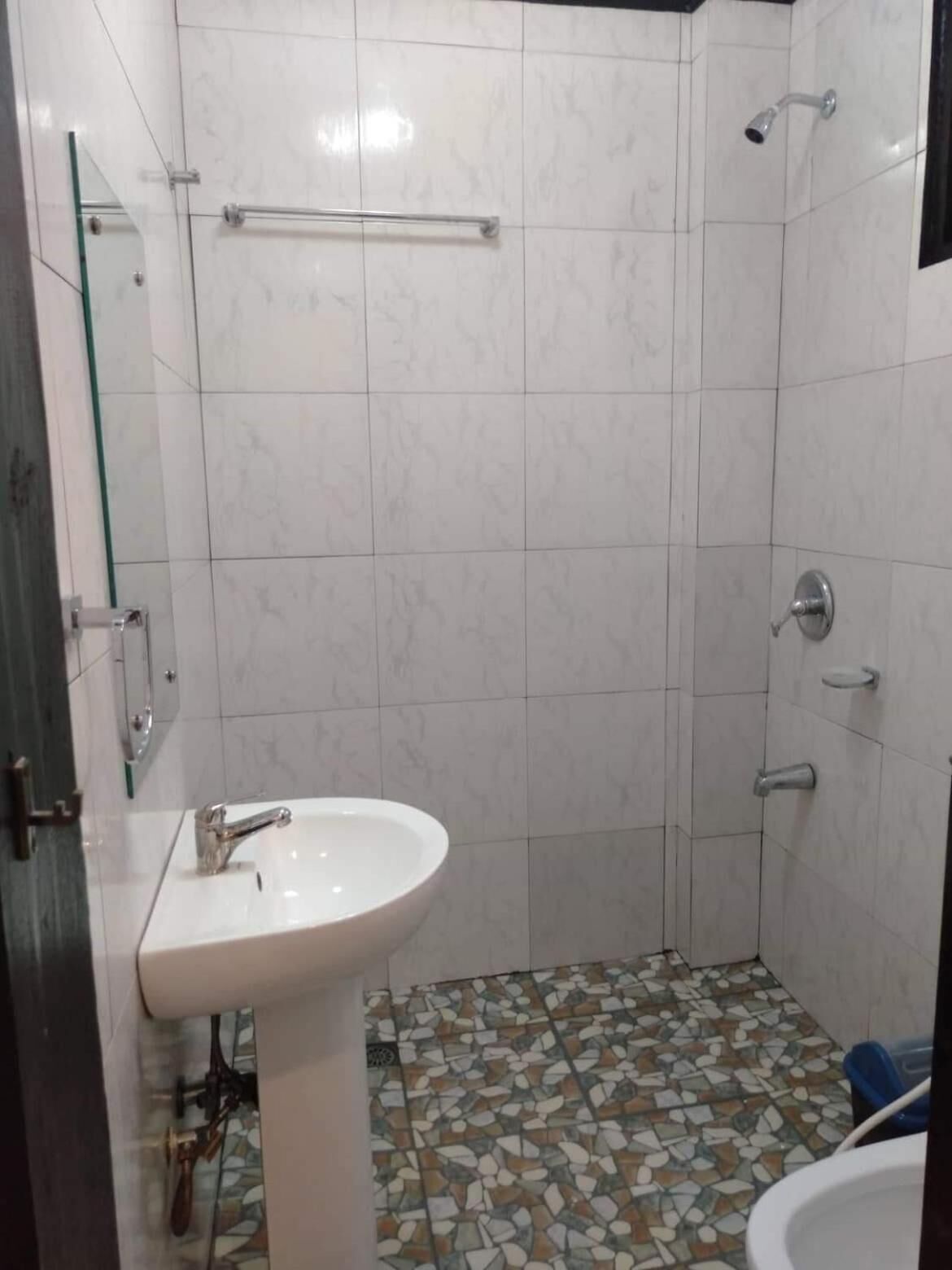 A bathroom with a white sink, a shower, and a tiled floor.