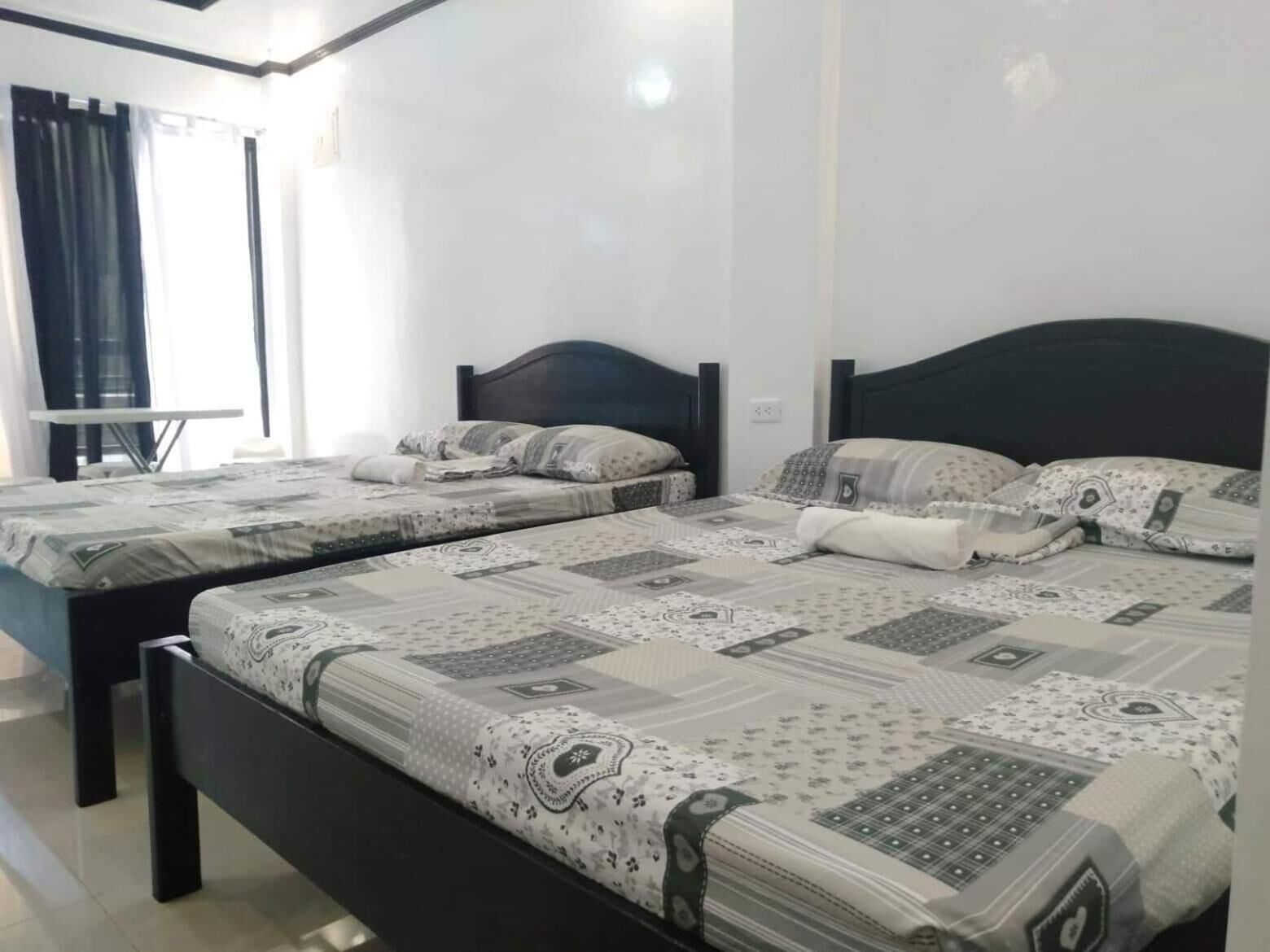 Habitación de hotel con dos camas, cada una con ropa de cama estampada y cabeceros oscuros.