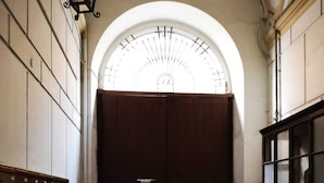 A hallway with a large arched doorway, a wooden bench, and a cabinet with glass doors. - Dimora Ruggiero (Naples)