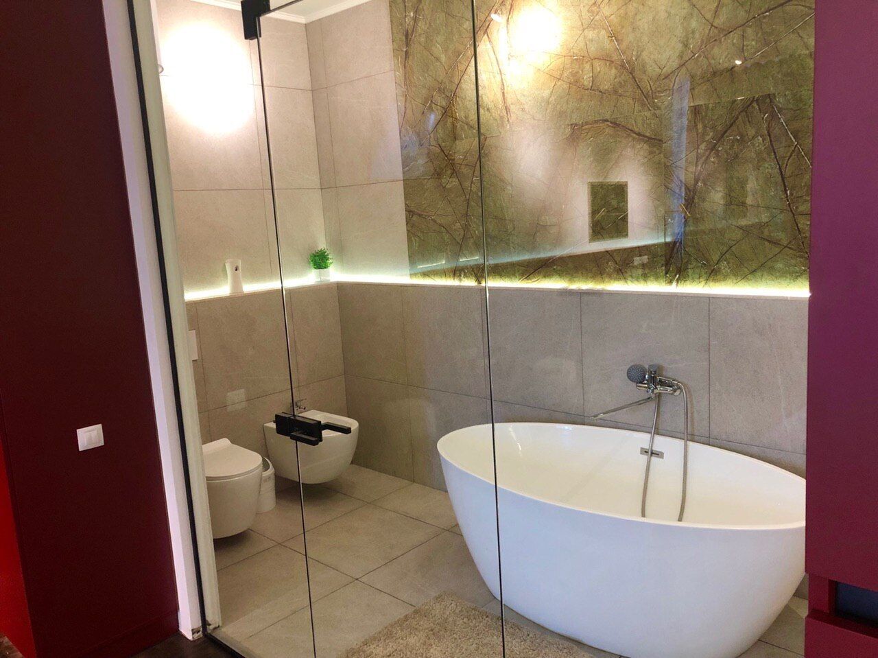 Un baño moderno con ducha envuelta en vidrio, inodoro independiente y una bañera ovalada grande.