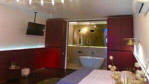 A modern bathroom with a freestanding bathtub, a large mirror, and a wall-mounted TV. - Beach Club Odessa Hotel (Odesa)