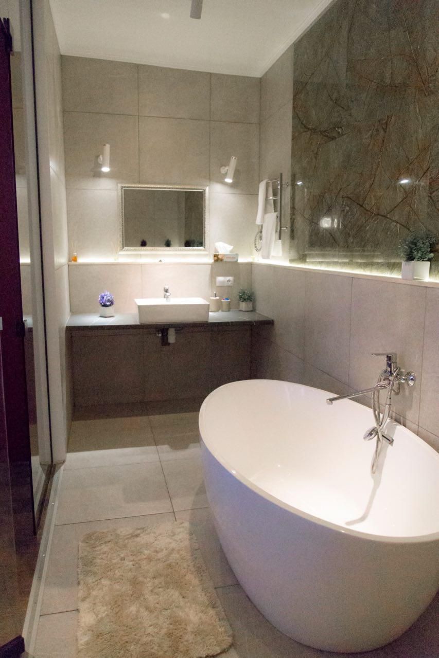 A modern bathroom with a freestanding bathtub, a vanity with a mirror, and a marble backsplash.