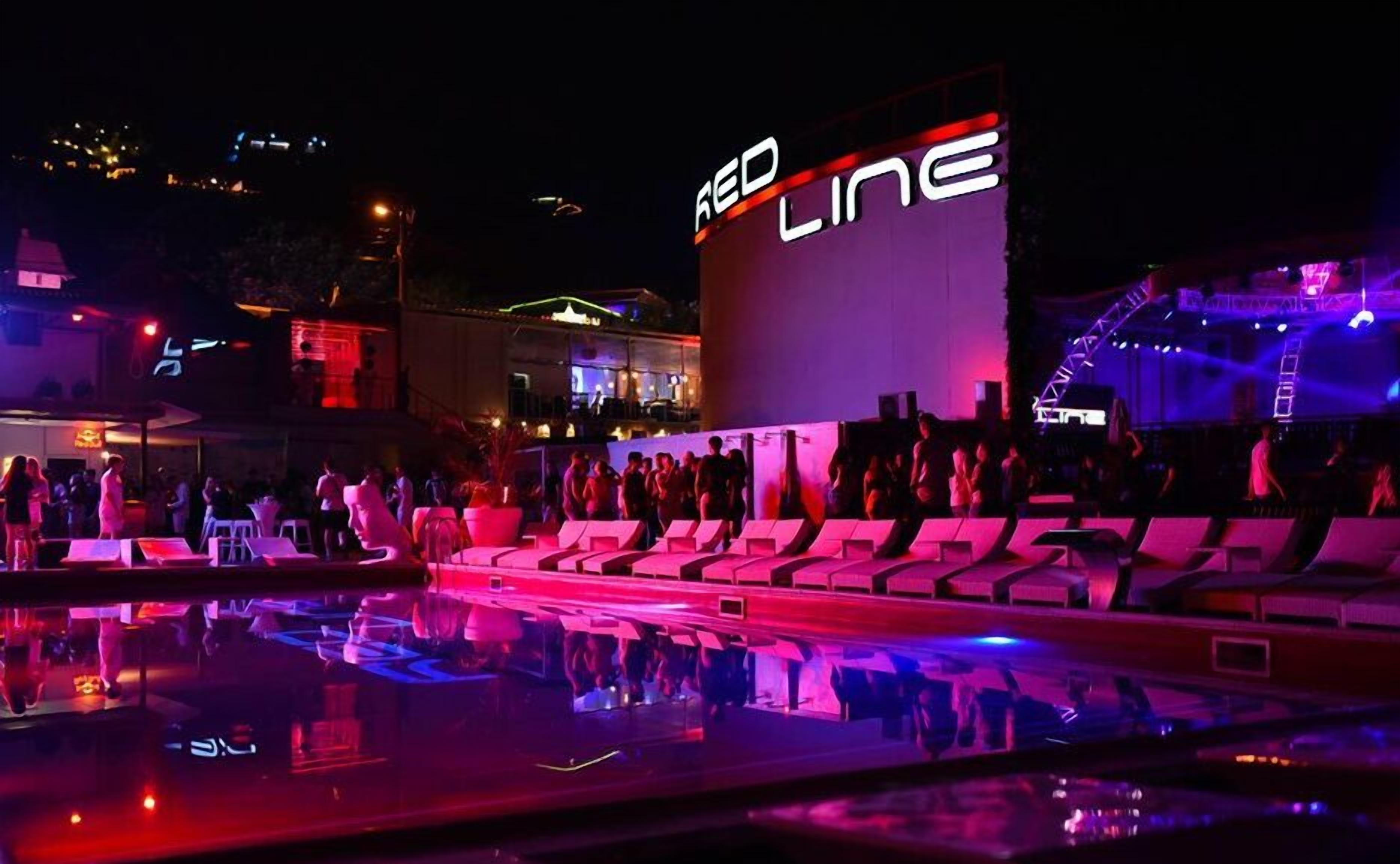A pool area with lounge chairs and a stage for performances.