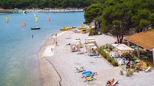 Une plage avec une eau cristalline, des parasols et des chaises longues.