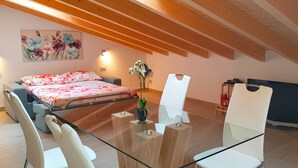 Un dormitorio moderno con una cama, una mesa de vidrio y un escritorio con una computadora.