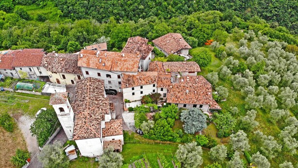 Vista aérea de un pueblo tradicional con edificios de tejas de arcilla, rodeado de exuberante vegetación y viñedos.
