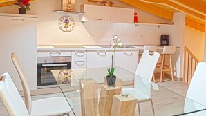 Una cocina moderna con armarios blancos, horno empotrado y un reloj en la pared.