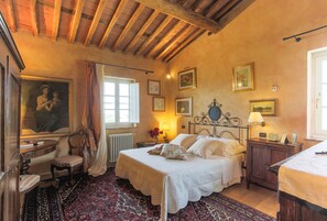 A bedroom with a bed, a chair, a desk, a radiator, and a window. - Meriggio Barn (Capannori)