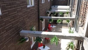 A courtyard with brick walls, multiple tables and chairs, and hanging planters. - Hotel Barrio Yungay (Santiago)