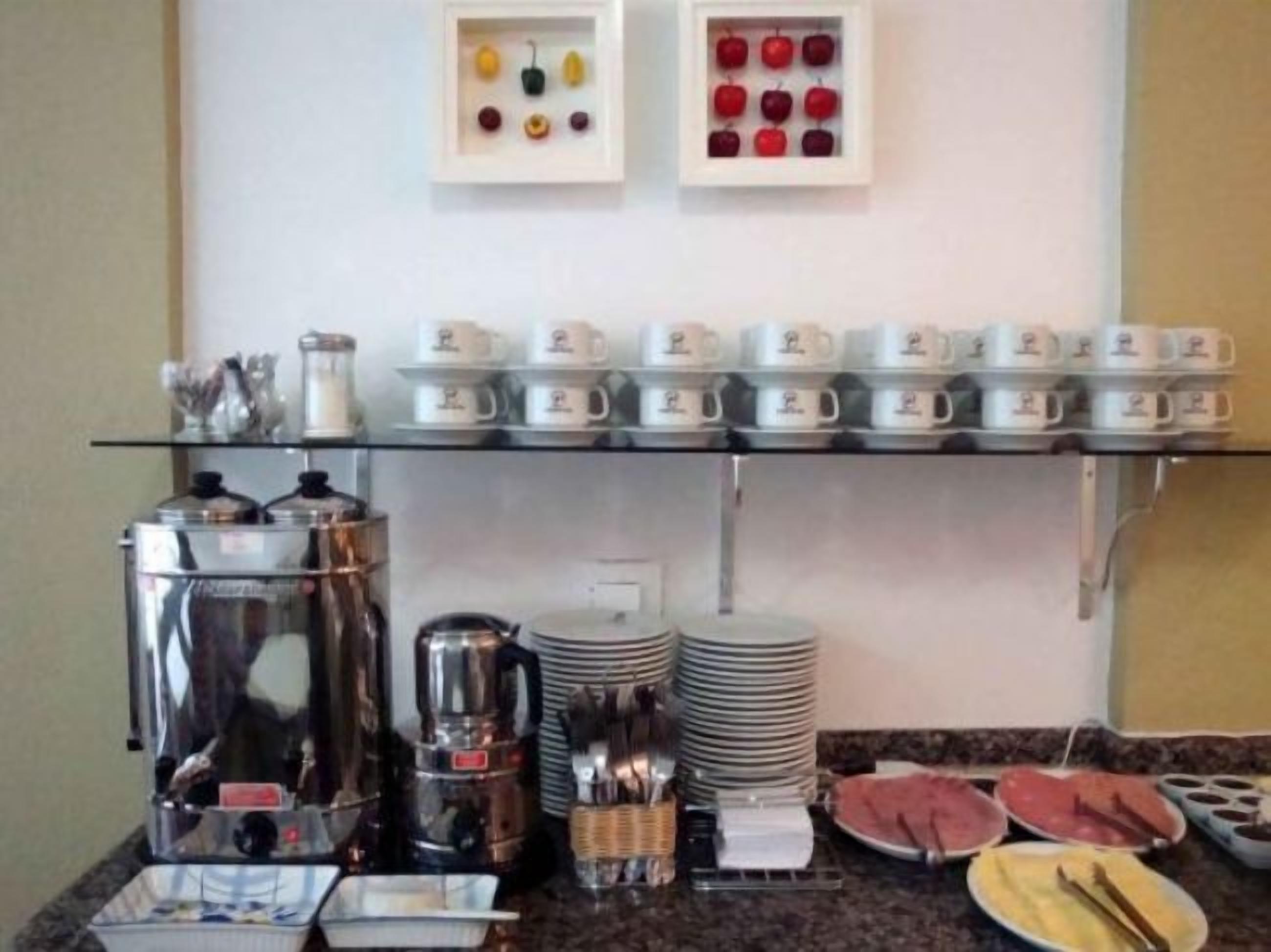 Disposição de buffet de café da manhã com máquinas de café, bules de chá e diversas opções de alimentos.