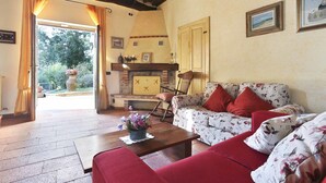 Ein gemütliches Wohnzimmer mit Kamin, einer floral gepolsterten Couch und einem Holztisch.