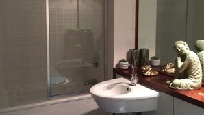 Une salle de bain avec une douche à parois de verre, un lavabo blanc et un miroir.